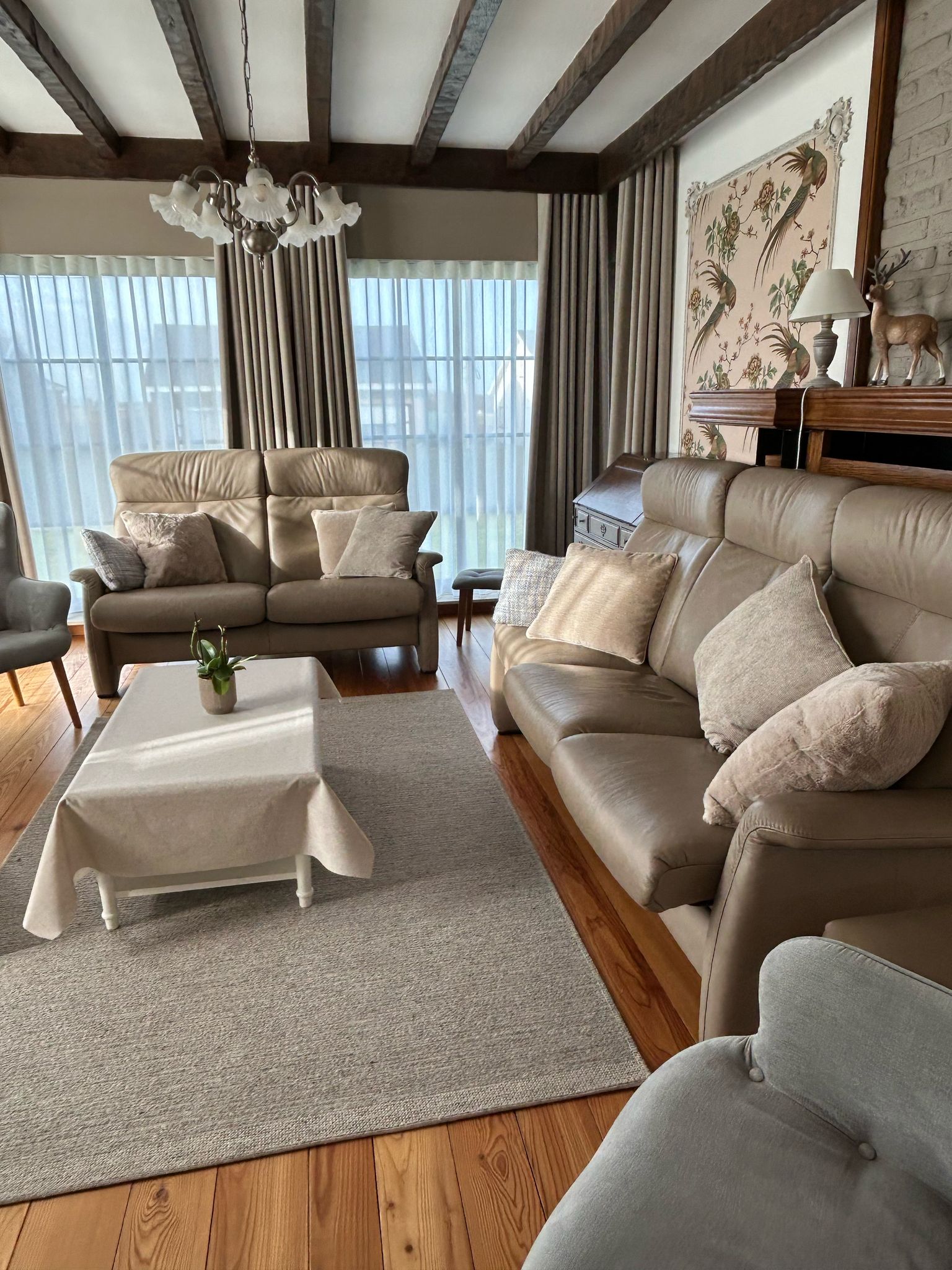 woonkamer met licht bruine lederen zetels, beige tapijt en salon tafel met beige tafellaken